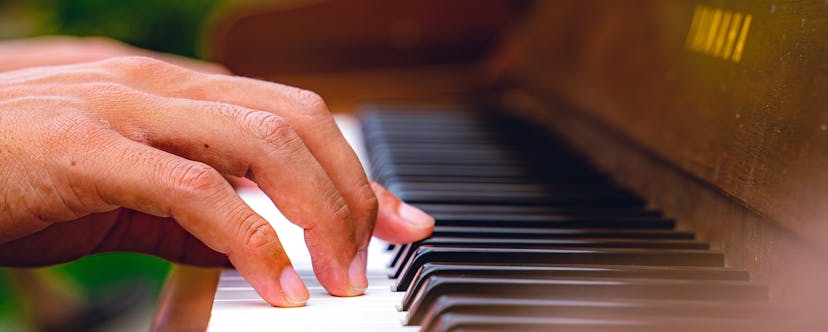 A hand playing an old piano