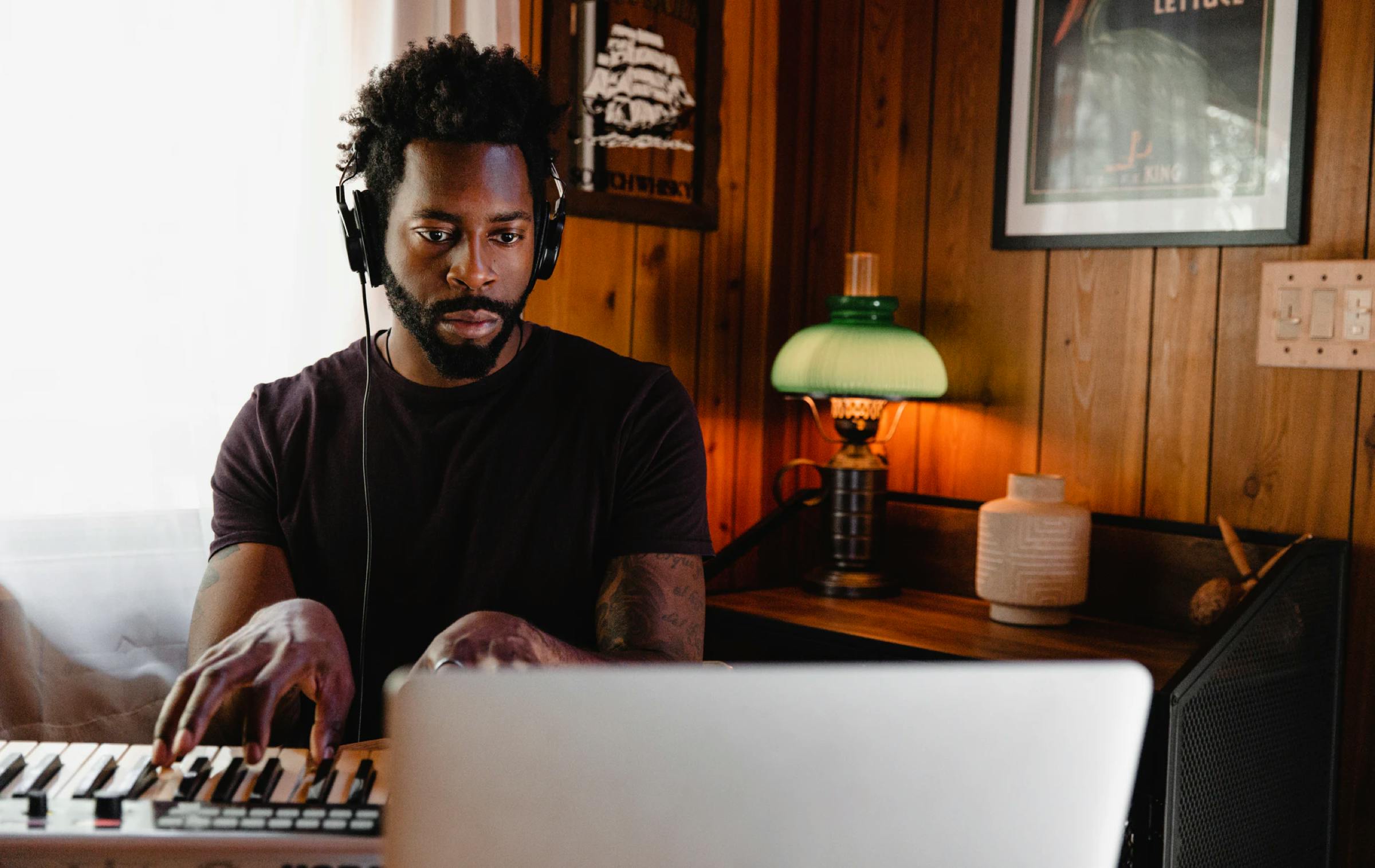 Man spielt Keyboard während er aufs Notebook schaut.