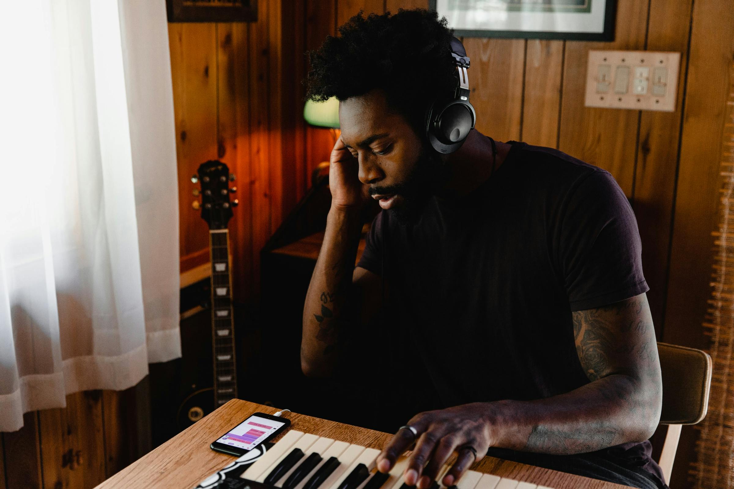 A man wears headphones and is playing a keyboard